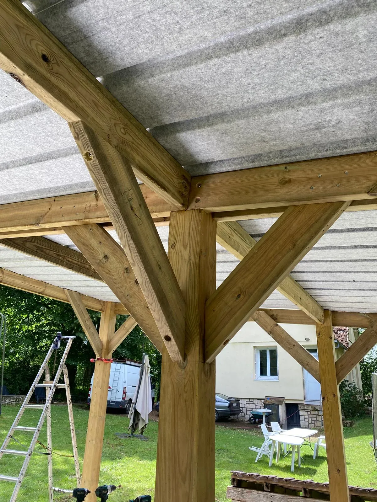 Détail de la charpente bois et des assemblages sous la toiture d'un carport, dans l'Aisne