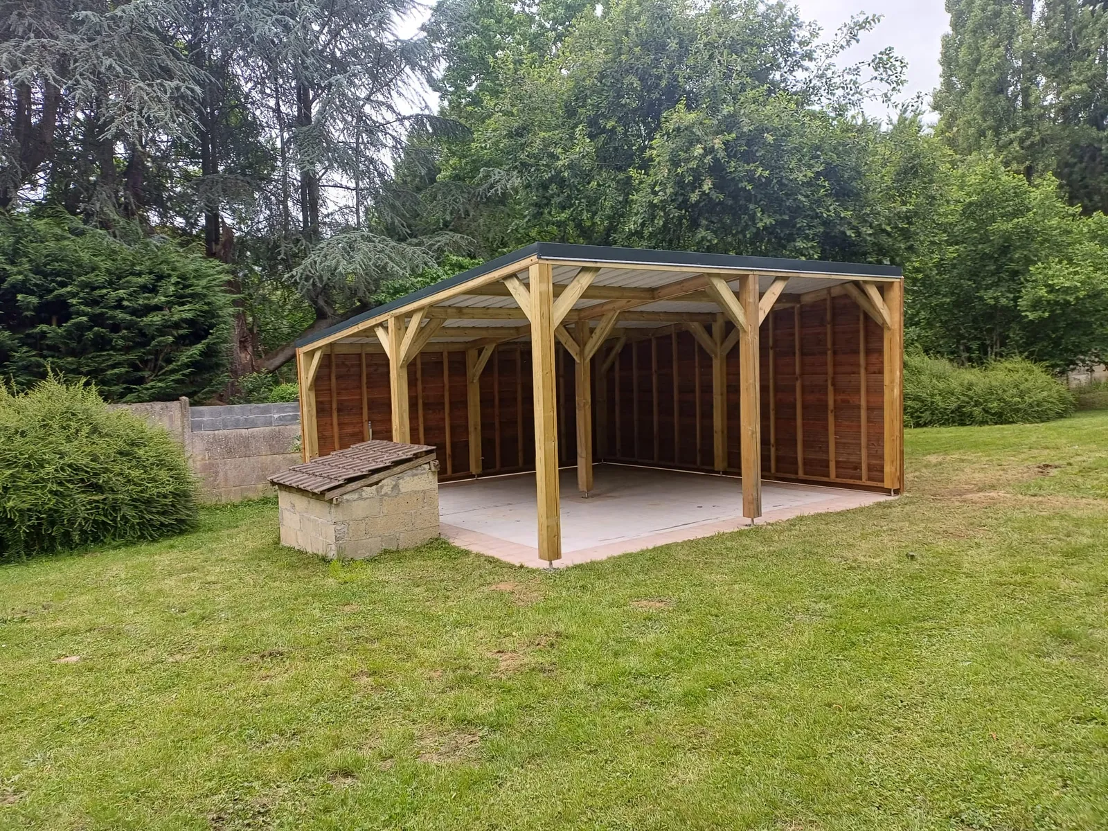 Carport bois avec bardage horizontal et toiture bac acier, posé dans un jardin dans l'Aisne