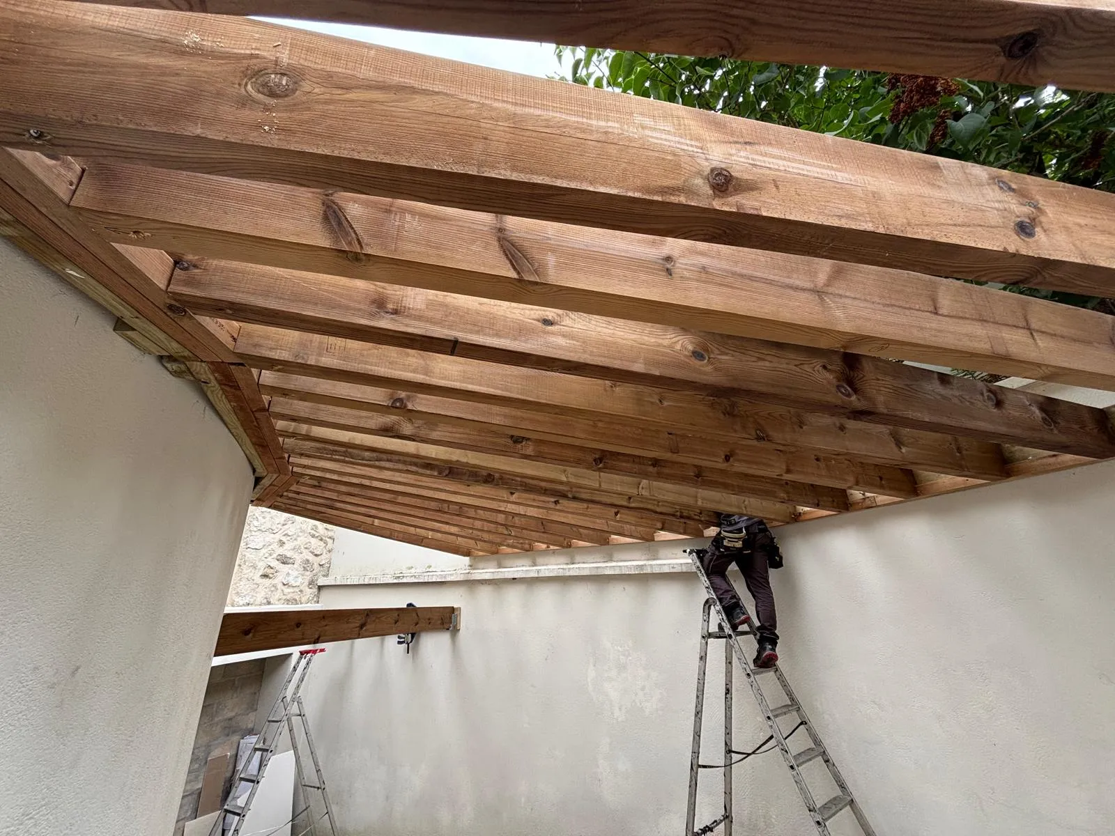Détail du solivage et des chevrons en bois d'une pergola vue par dessous