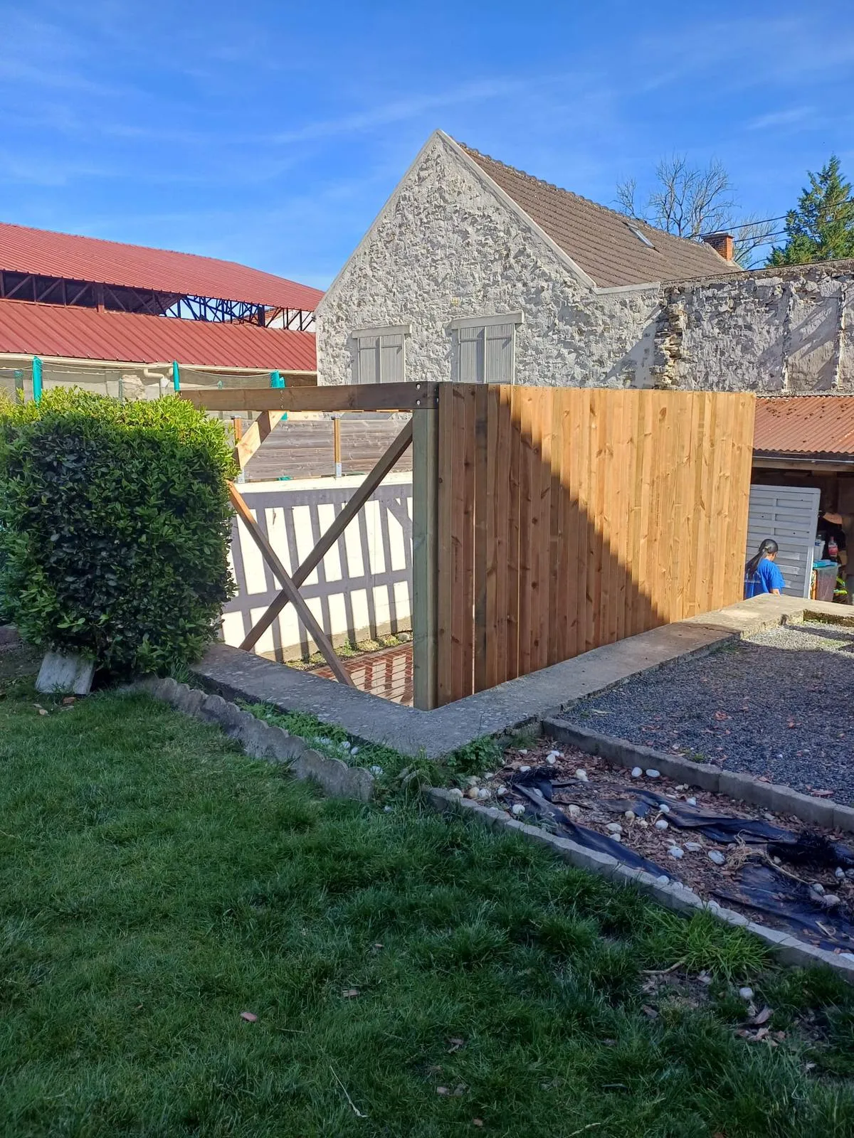 Brise-vue en bois plein d'une pergola côté jardin, avec poteau et contreventement, réalisé dans l'Aisne