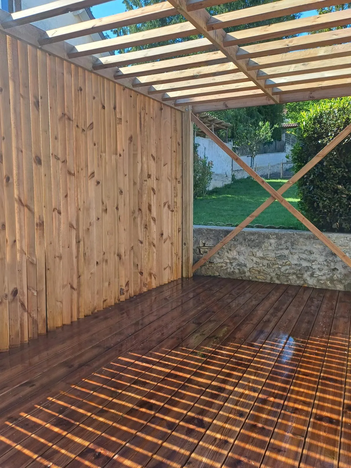 Pergola bois avec charpente apparente et brise-vue à lames, ouverte sur le jardin, posée sur terrasse en bois dans l'Aisne