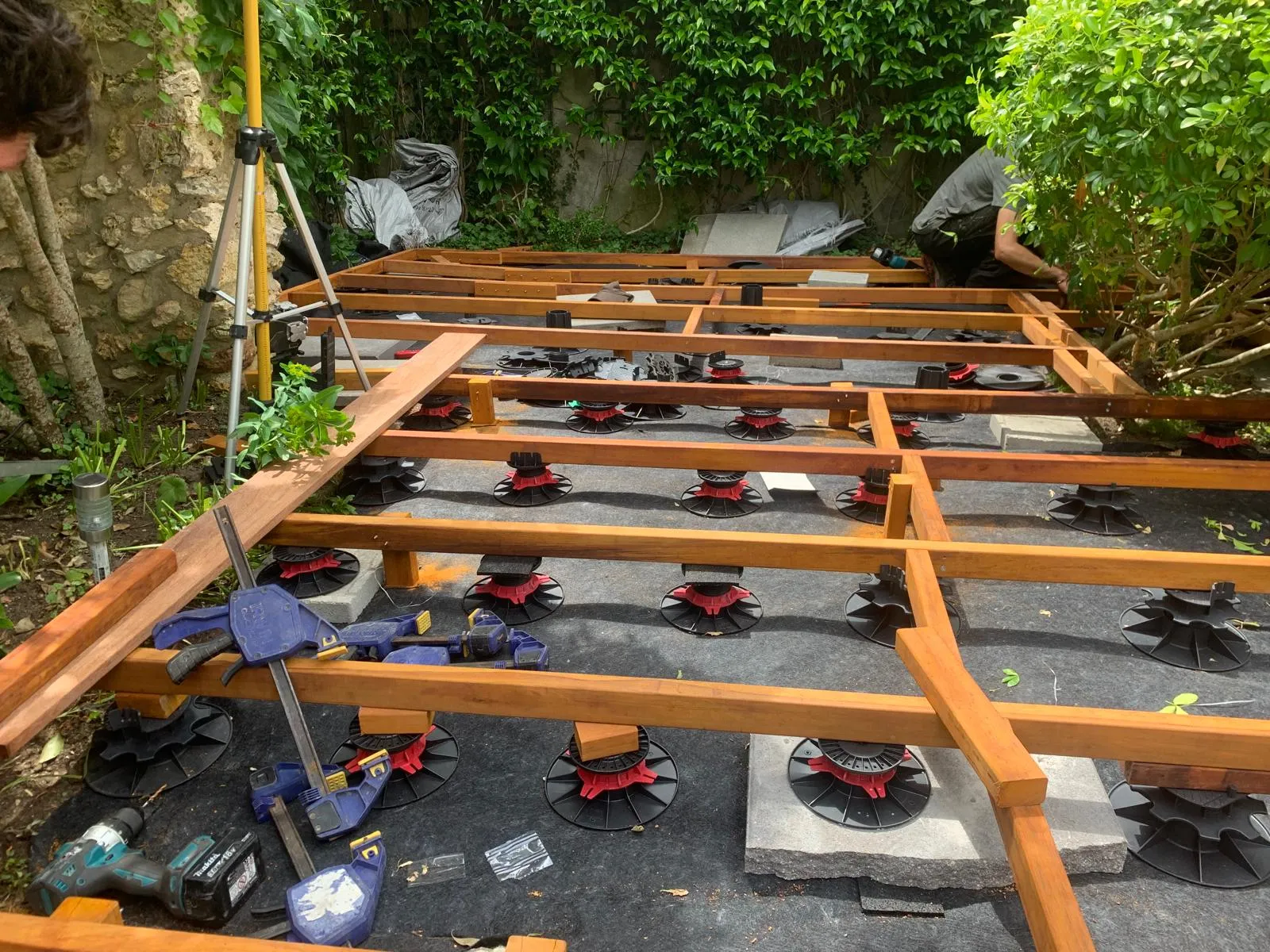 Détail des plots réglables et de la trame de lambourdes d'une terrasse bois, à Chambourcy