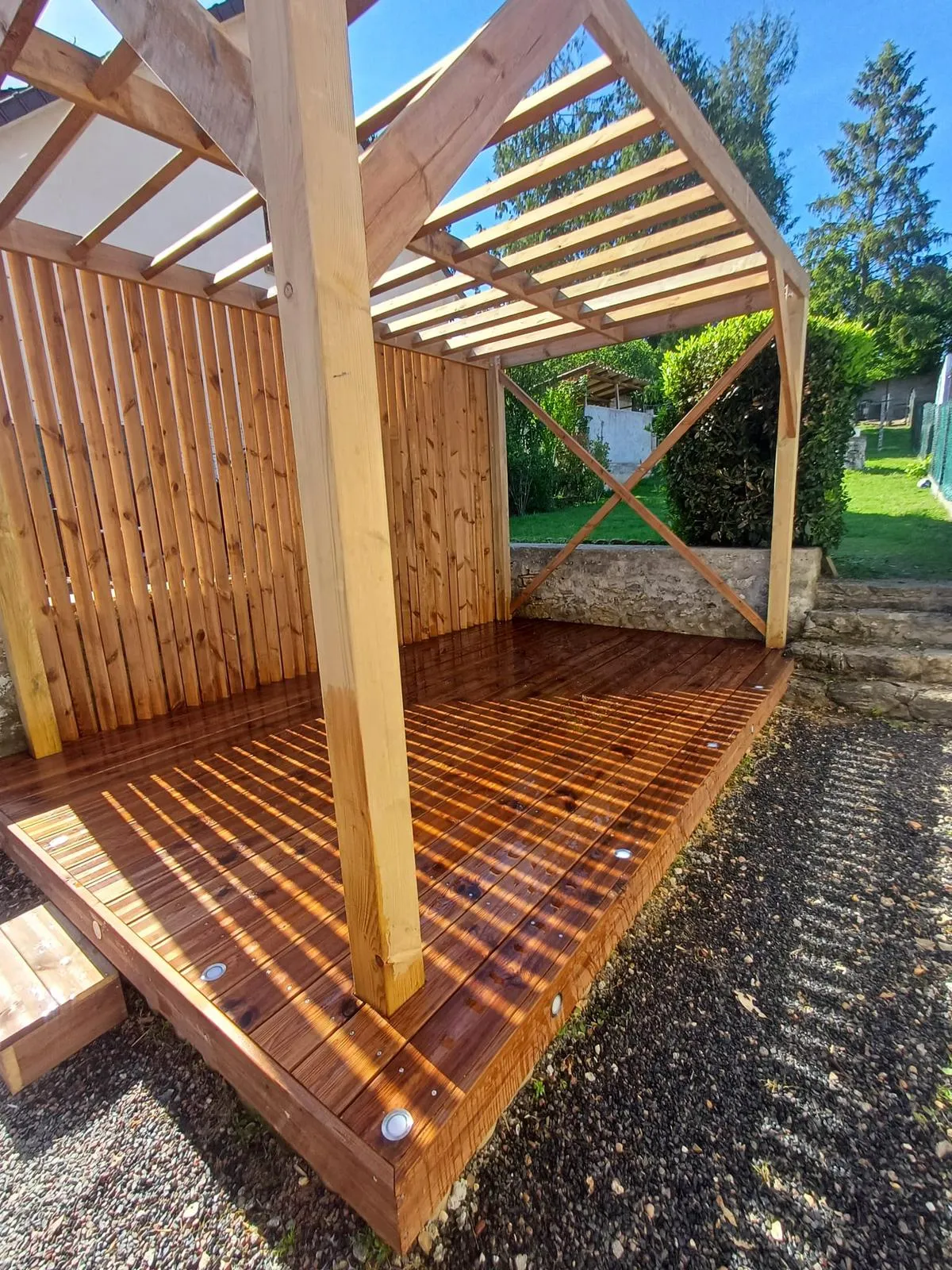 Terrasse surélevée en bois surmontée d'une pergola bois, vue extérieure dans un jardin de l'Aisne