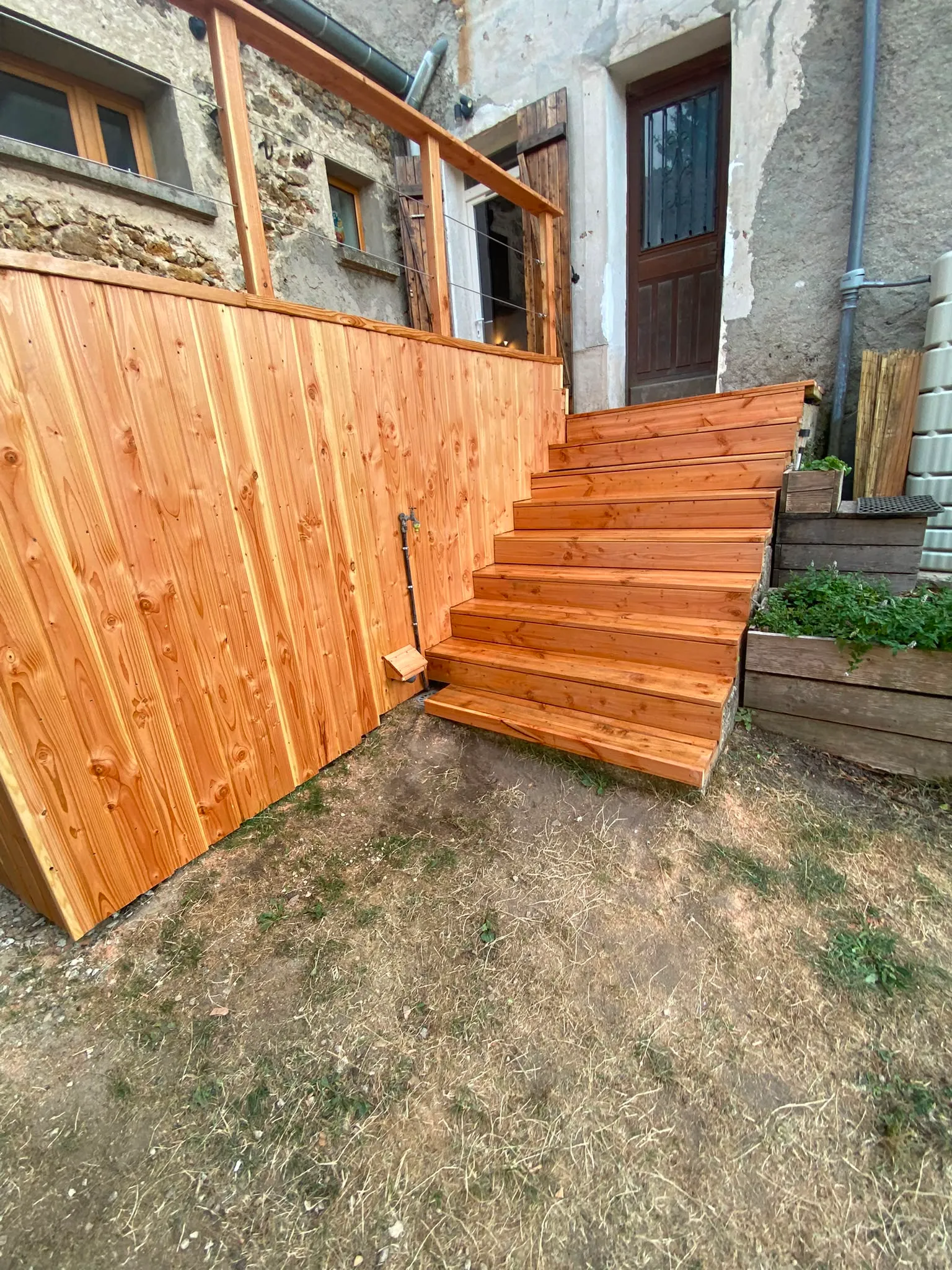 Escalier en bois massif et palissade à lames verticales d'une terrasse surélevée, réalisés par La Planète Bois en Essonne